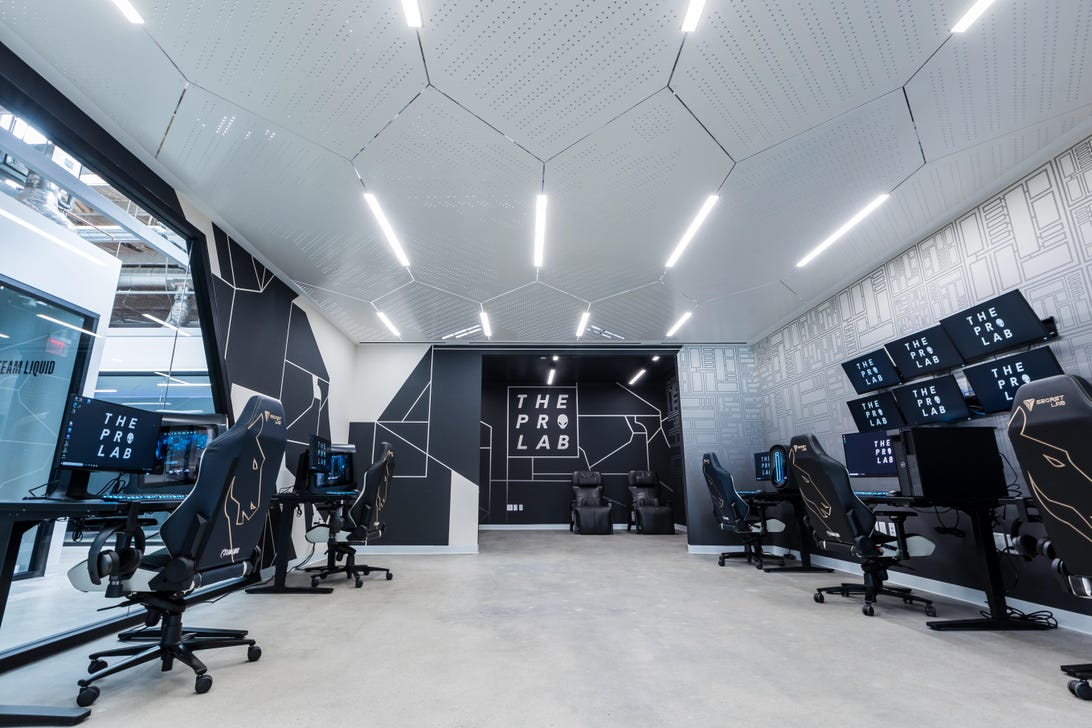 Pro Lab Team Liquid ze stanowiskami komputerowymi, sześciomonitorową stacją NeuroOlympics i fotelami relaksacyjnymi o zerowej gramaturze — wszystko ozdobione komputerami Alienware i logo Team Liquid.