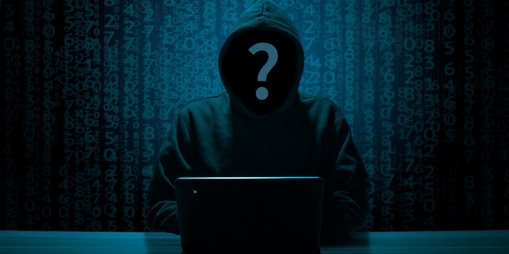 anonimowa postać w kapturze na laptopie ukryta znakiem zapytania